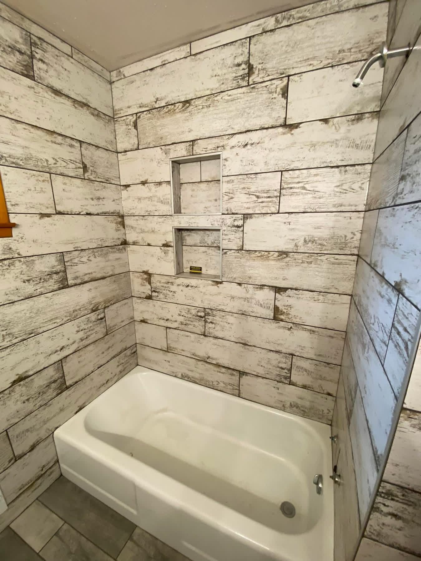 Whitewashed wood-look tub surround with two stacked recessed niches.