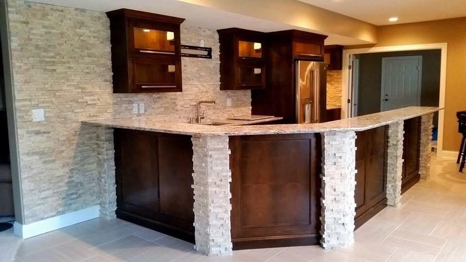 Stacked-stone bar walls and columns with dark cabinetry and a tiled floor.